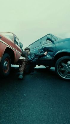 a man kneeling down next to a parked car