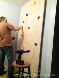 a man is using a drill to fix a wall with rock climbing equipment on it