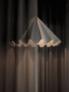 a lamp that is sitting on top of a table in front of a curtained window