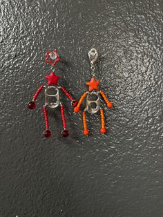 two orange and red earrings on a black surface