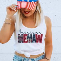 a woman wearing an american memaw t - shirt while holding her hat in front of her face