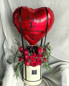 a red heart shaped balloon sitting on top of a vase filled with flowers