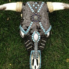 a cow's head with blue and white designs on it is laying in the grass