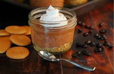 a glass jar filled with dessert sitting on top of a wooden table next to cookies