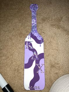 a purple and white spatula laying on the floor