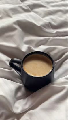 a cup of coffee sitting on top of a bed