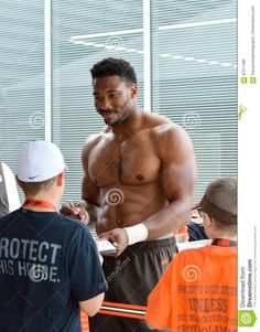 a shirtless man with no shirt talking to two other men in an office building