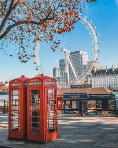 two red telephone booths sitting in front of a ferris wheel