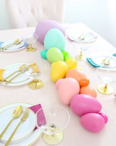 the table is set with colorful balloons and place settings for an easter egg themed party