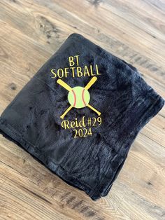 a black t - shirt with a softball bat and ball embroidered on the front that says, bt softball