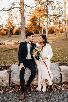 a man and woman sitting on a log kissing