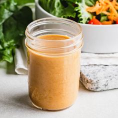 a glass jar filled with dressing next to a salad