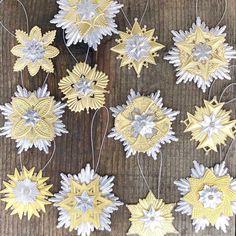 paper snowflakes are hanging from strings on a wooden table with string attached to them