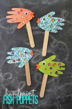 three handprinted fish puppets on wooden sticks