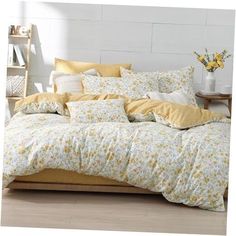 a bed with yellow and white comforters in a room next to a wooden table