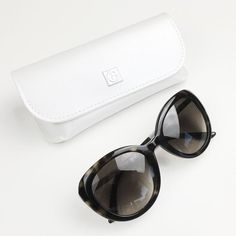 a pair of sunglasses sitting on top of a white table next to a case and eyeglasses