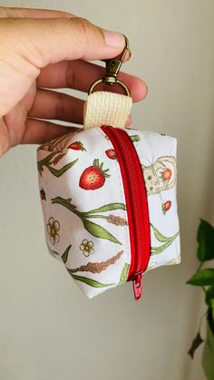 a hand holding a small zippered pouch with a red ribbon around it and an animal design on the front