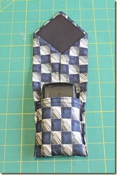 a cell phone in a pocket on top of a cutting mat with scissors and tape