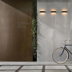 a bike parked in front of a hotel entrance with plants growing on the wall behind it