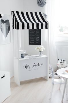 a white and black striped awning in a small room with a table, chairs, and pictures on the wall