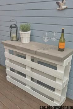 an outdoor bar made out of pallets with wine glasses and a bottle on top