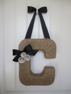 the letter c is made out of yarn and has a black bow on it's side