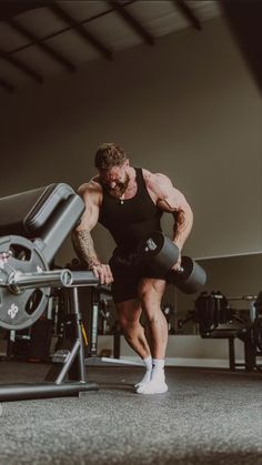 a man doing squats on a bench in a gym with dumbbells behind him