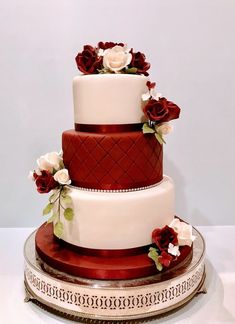 a three tiered cake with red and white flowers