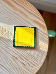 a wooden table with a small yellow square on the top and green border around it