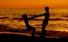 a man and woman dancing on the beach at sunset