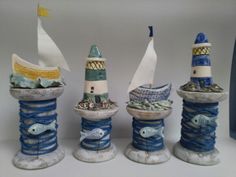 three ceramic lighthouses with sailboats and fish on them