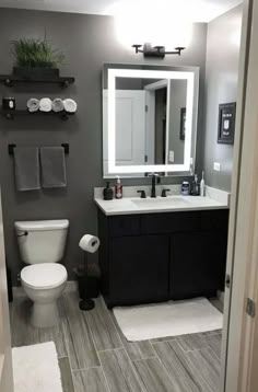 a white toilet sitting next to a sink in a bathroom under a mirror and lights