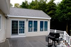 a piano sitting on top of a wooden deck next to a white fence and trees