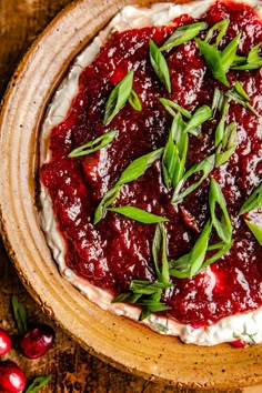 a wooden bowl filled with whipped cream and cranberry sauce on top of a table