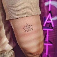 a woman's arm with a small lotus tattoo on it