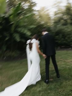 a bride and groom walking through the grass