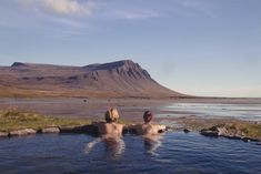 two people sitting in a hot tub with mountains in the background