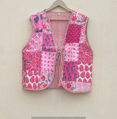 a pink and white patchwork vest hanging on a wall