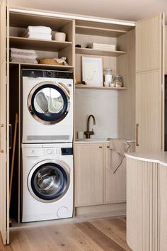 a washer and dryer in a room with wooden flooring, cabinets and shelves