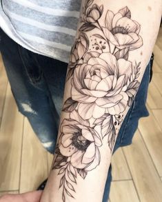 a woman's arm with flowers and leaves tattooed on the wrist, in black ink