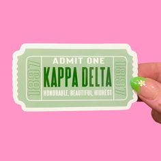 a person holding up a green ticket for kappa delta on a pink background