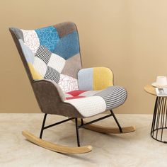 a rocking chair with patchwork fabric on the back and seat, next to a small side table