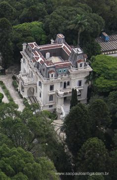 an aerial view of a mansion surrounded by trees