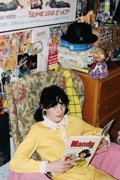 a woman sitting in a chair reading a magazine