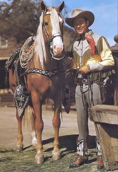 a man standing next to a brown and white horse