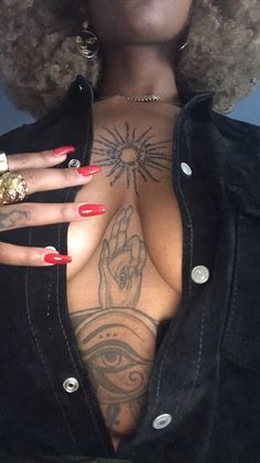 a woman with tattoos on her chest and red nails is posing for the camera while wearing a black jacket