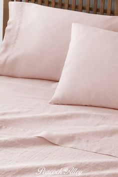 a bed with pink sheets and pillows on it