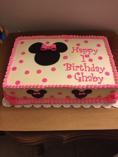 a pink and white birthday cake with minnie mouse on it