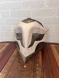 a helmet sitting on top of a wooden table next to a white brick wall in the background