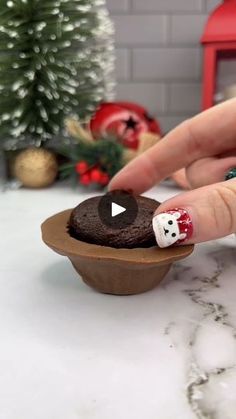 a person with red and white nail polish on their nails next to a cupcake